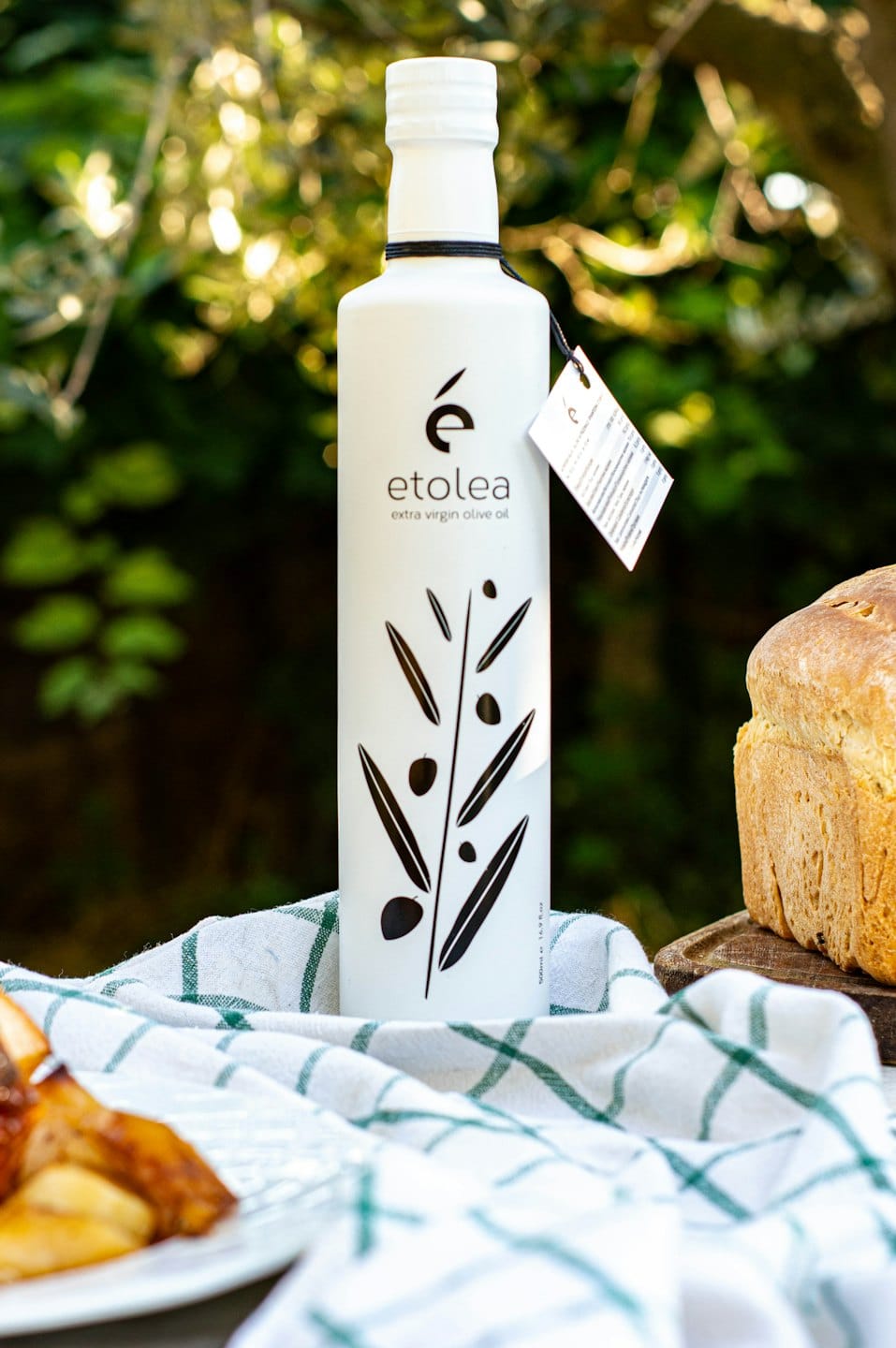 Bottiglia di olio d'oliva etolea e pane su una tovaglia a scacchi.